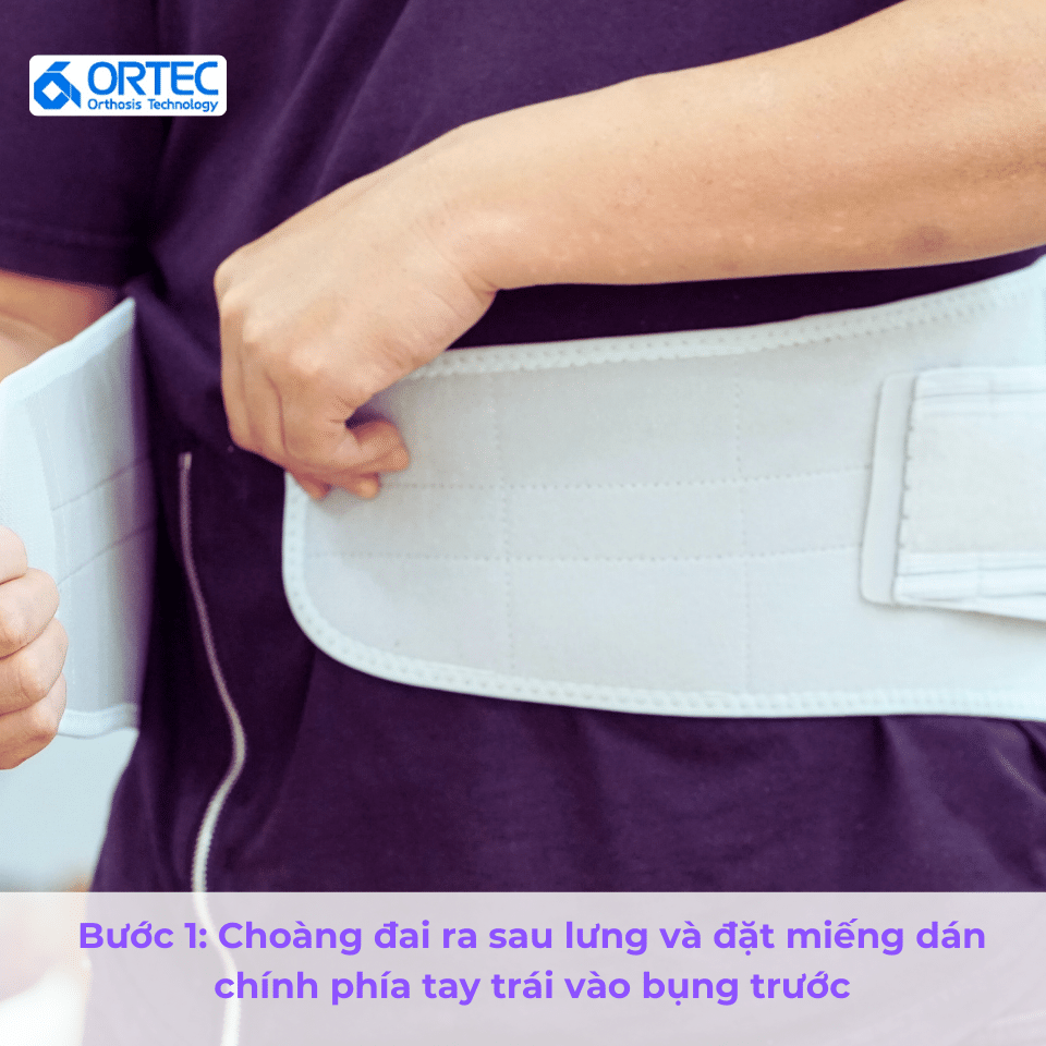 Bước 1: Choàng đai ra sau lưng và đặt miếng dán chính phía tay trái vào bụng trước